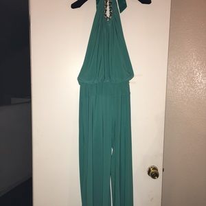 Cache turquoise jumpsuit with gold chain necklace.